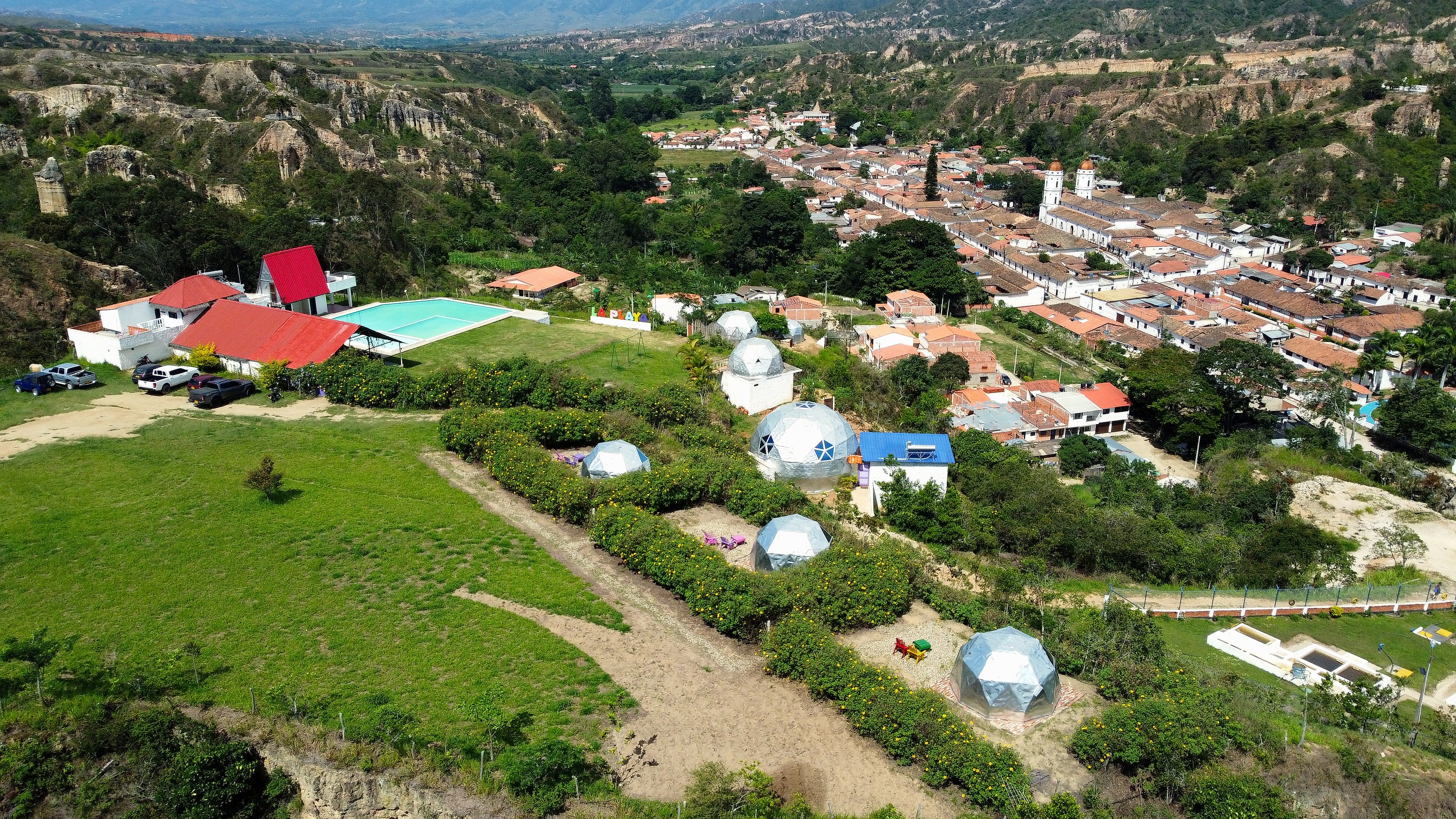 Vista aérea del glamping TAVOLANDIA: domos, piscina y zonas verdes en La Playa de Belén