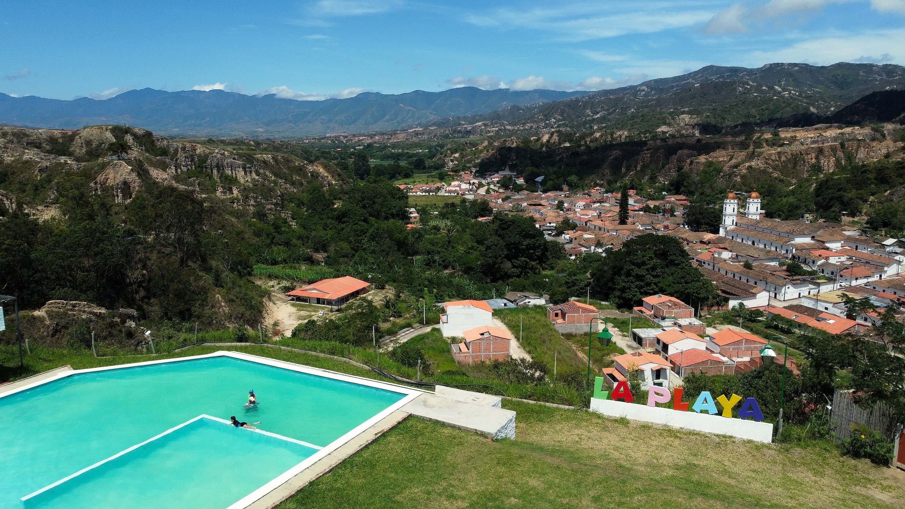 Vista aérea de TAVOLANDIA: domos, piscina y zonas verdes entre montañas